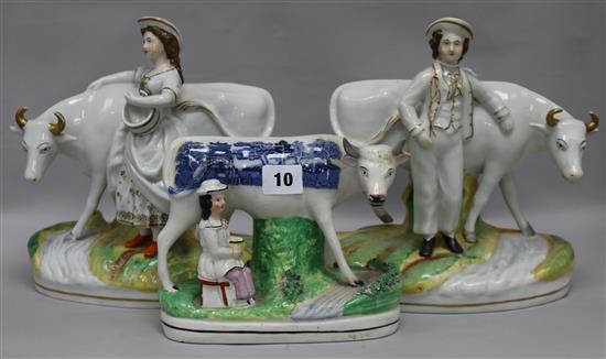 A pair of 19th century Staffordshire porcelain groups of a dairy boy and a dairy girl standing by a cow and a similar group printed wit